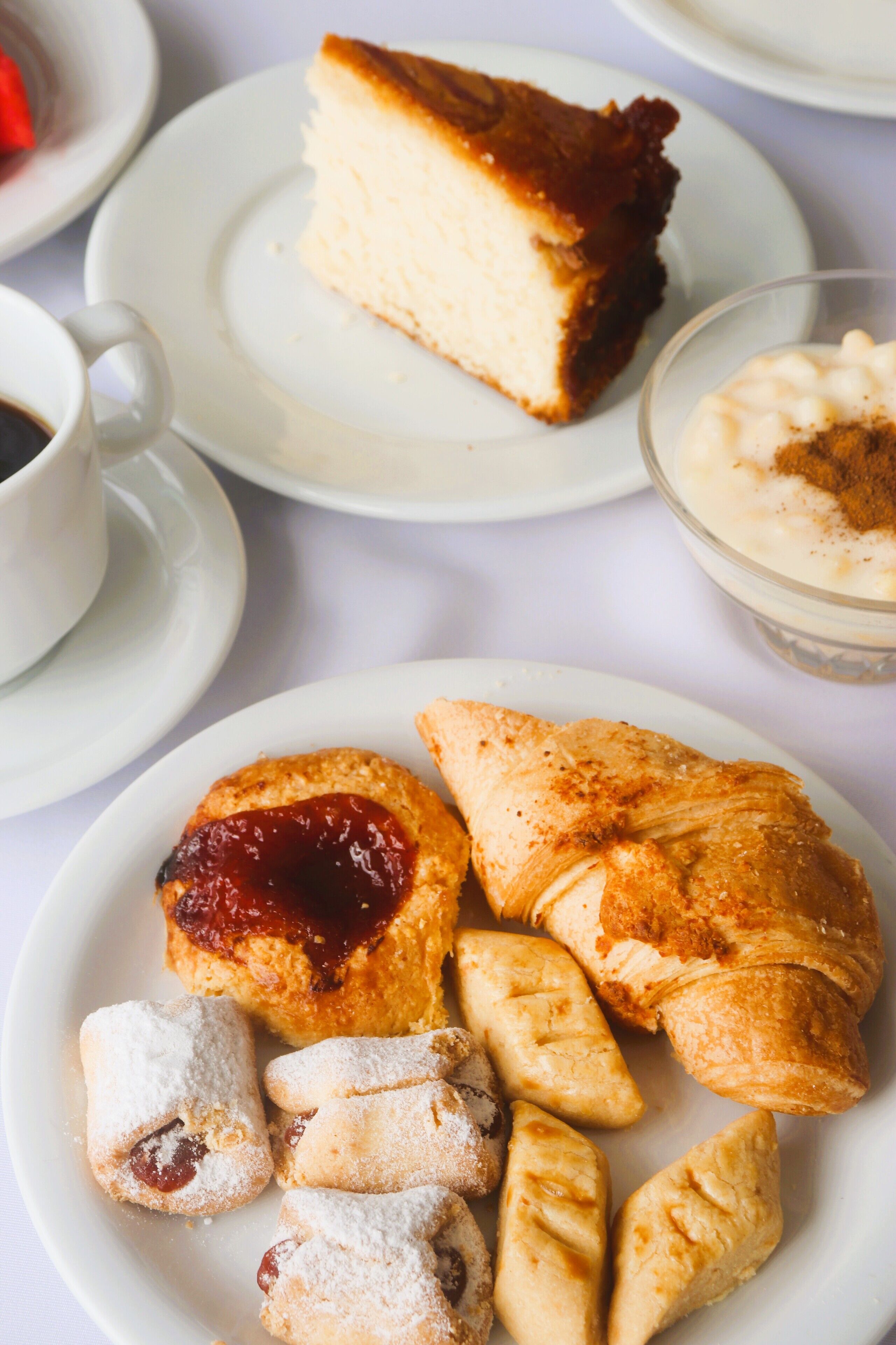 A variety of pastries and desserts on plates, including a slice of cake and scones.