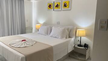 Une chambre d’hôtel avec un lit soigneusement fait, deux lampes de chevet, un téléphone et trois œuvres d’art encadrées accrochées au mur.
