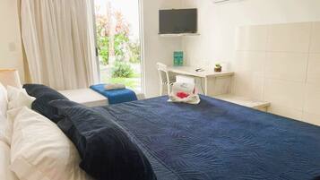 Ein Hotelzimmer mit einem großen Bett, einem Schreibtisch mit Stuhl, einem Fernseher und einem Fenster mit Vorhängen.