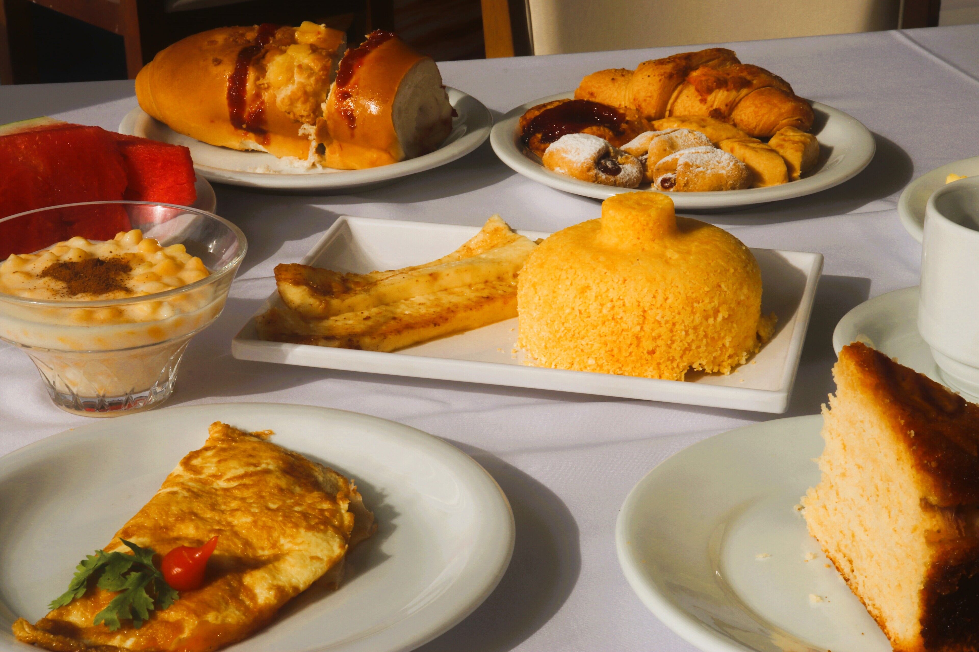 A table with various breakfast items including pastries, a fruit, and a dessert.