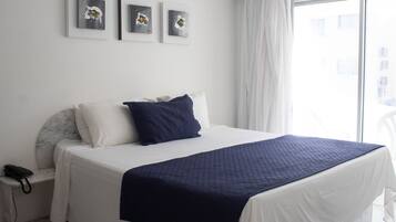 Habitación de hotel con una cama grande, una mesita de noche con teléfono y tres obras de arte enmarcadas en la pared.