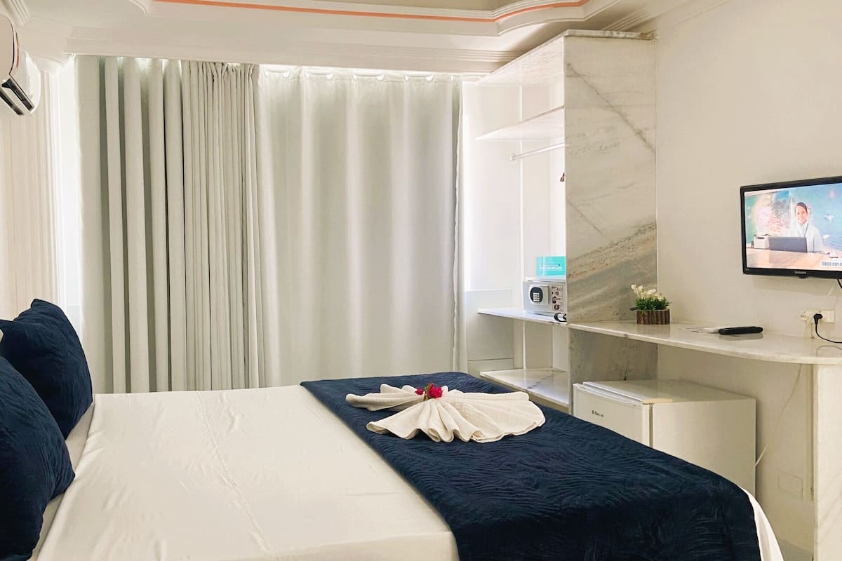 A hotel room with a bed, a desk, a television, and a bathroom.