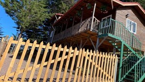 Eine Holzhütte mit einem Balkon und einer grünen Treppe.