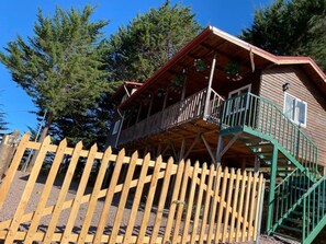 Eine Holzhütte mit einem Balkon und einer grünen Treppe.