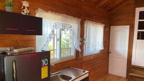 Eine kleine Küche mit Kühlschrank, Spüle und Holzschränken.