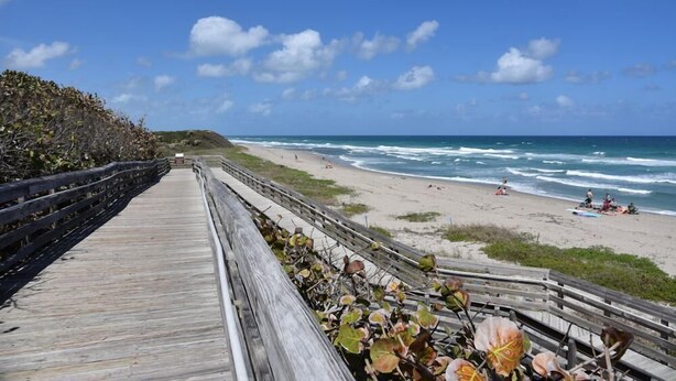 A wooden boardwalk leading to a beach with ocean views. - The Villa #1 (North Palm Beach)