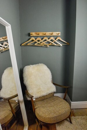A room with a chair and a wooden hanger rack against a wall. - Juniper Cottage is a quaint, two-bedroom Grade II listed property featuring white wooden cladding. (Whitstable)