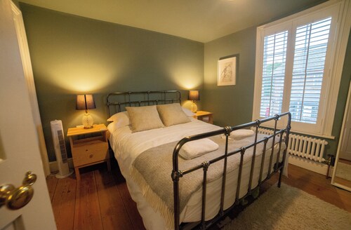 Juniper Cottage is a quaint, two-bedroom Grade II listed property featuring white wooden cladding.