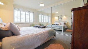 Ein Schlafzimmer mit einem großen Bett, einem Kleiderschrank, einem Spiegel und einem Fenster.