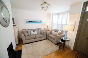 A living room with two sofas, a chandelier, a painting, a lamp, and a door.