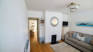 Ein Wohnzimmer mit Kamin, einer Couch, einem Fernseher und einer Deckenleuchte.