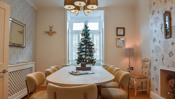 A dining area with a round table, six chairs, a Christmas tree, and a chandelier. - Harbour House is a lovingly refurbished and centrally located beautiful three storey house, sleeping 9 guests, with private parking. (Whitstable)