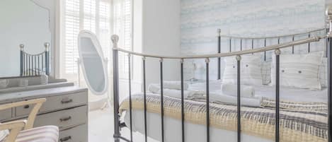 Un dormitorio con una cama, un aparador, una silla y una ventana.