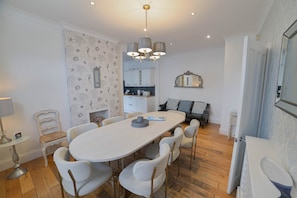A modern kitchen with white cabinets, a dining table with chairs, and a chandelier. - Harbour House is a lovingly refurbished and centrally located beautiful three storey house, sleeping 9 guests, with private parking. (Whitstable)