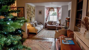 Ein gemütliches Wohnzimmer mit Sofa, Sesseln, Couchtisch und Weihnachtsbaum.
