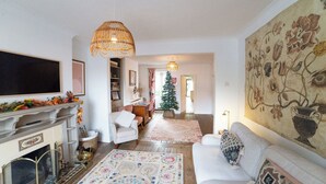 Ein Wohnzimmer mit Kamin, Sofa und Weihnachtsbaum.