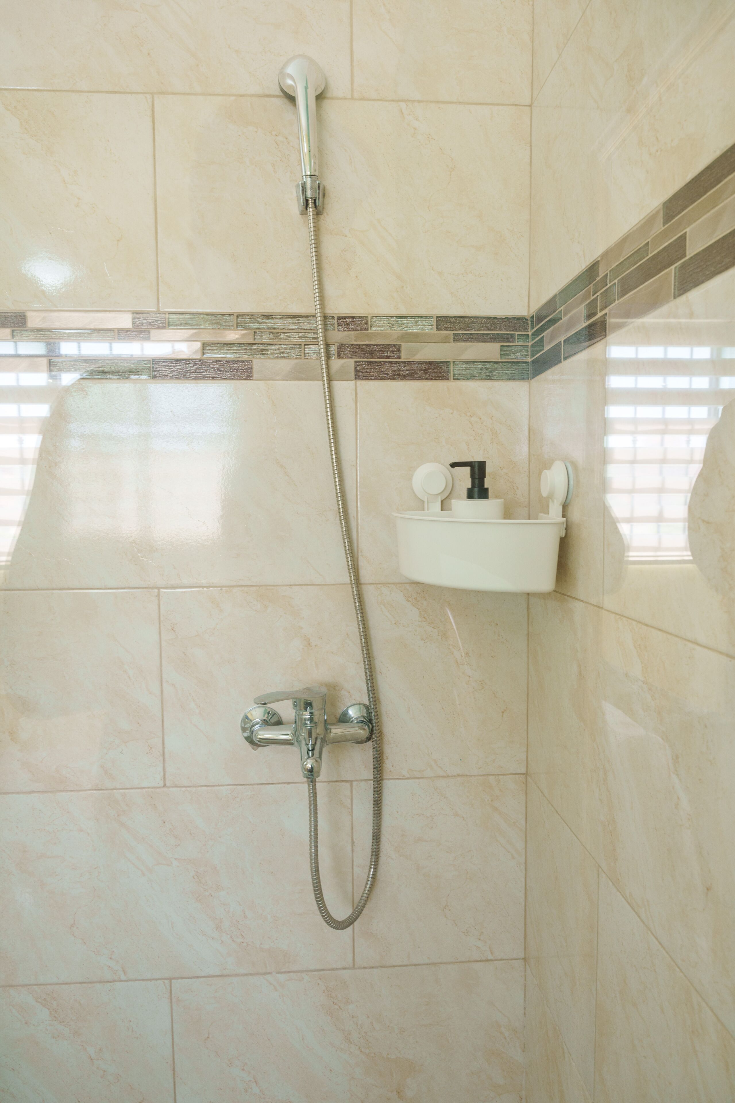 Eine Dusche mit Handbrause und Wandarmatur.