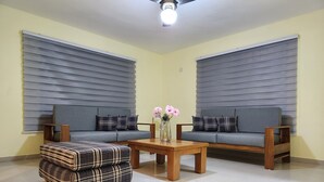 A living room with two grey sofas, a wooden coffee table, and a plaid ottoman. - La Casona MC (La Romana)