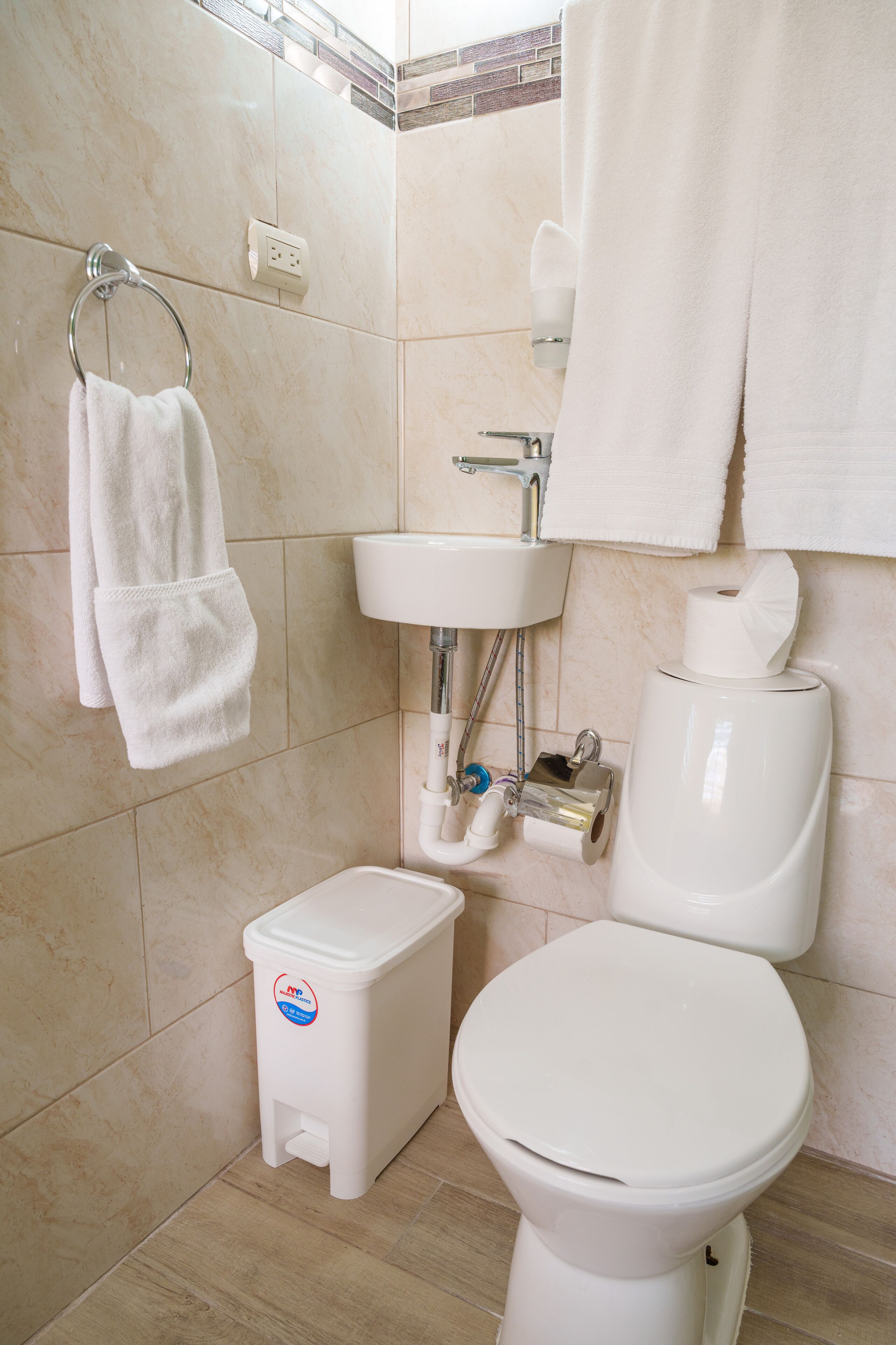 Une salle de bain avec des toilettes, un lavabo et une petite poubelle.