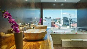 A modern bathroom with a large bathtub, two bowls, and a wooden vanity.
