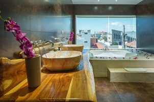 A modern bathroom with a large bathtub, two bowls, and a wooden vanity.