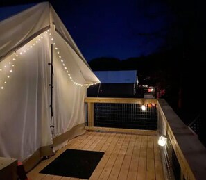A tent with string lights, a wooden deck, and a railing. - Trout Tent at Rusty's Roost River Camp (Green Mountain)