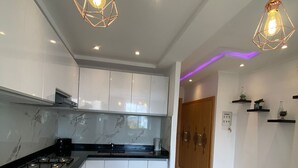Une cuisine moderne avec des armoires blanches, un comptoir noir et deux luminaires suspendus.