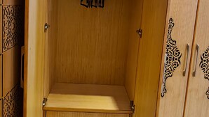Une armoire en bois avec un banc, des tiroirs et un espace pour suspendre les vêtements.
