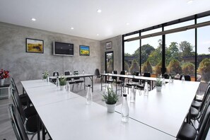 A conference room with a long table, chairs, potted plants, and artwork on the walls. - White Knot Khao Yai (Pak Chong)