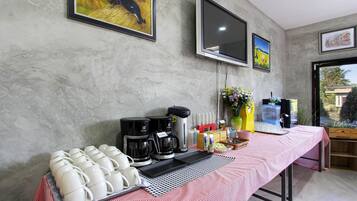 A breakfast setup with coffee makers, mugs, and a water dispenser on a table.