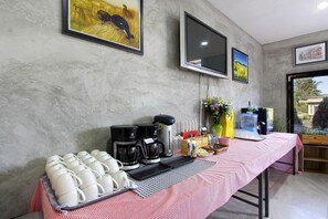 A breakfast setup with coffee makers, mugs, and a water dispenser on a table. - White Knot Khao Yai (Pak Chong)