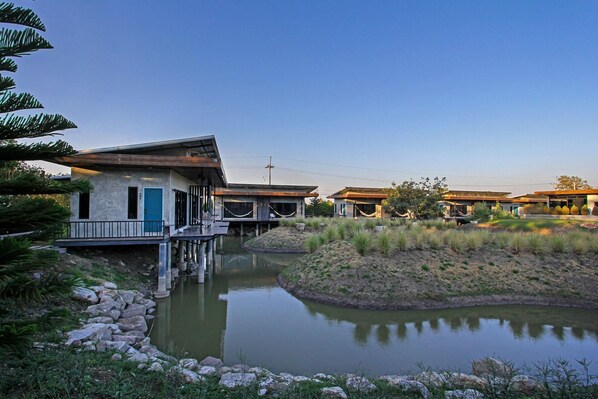 Un resort moderno con varias construcciones, una fuente central y un muelle.