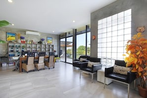 A spacious room with a dining area, a sofa, and a large window providing a view outside. - White Knot Khao Yai (Pak Chong)