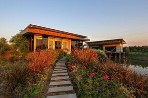 A modern building with a 'Lobby' sign, a 'Welcome' sign, and a pathway leading to a water body. - White Knot Khao Yai (Pak Chong)