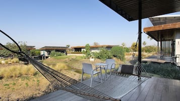A hammock on a wooden deck with a view of houses and greenery.