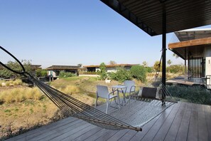 Una hamaca en una terraza de madera con vista a casas y follaje.