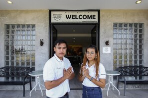 A building entrance with a 'WELCOME' sign, a glass door, and two tables with chairs outside. - White Knot Khao Yai (Pak Chong)