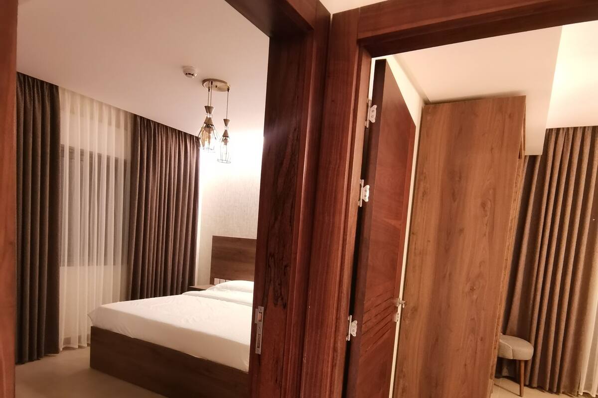 A bedroom with a large bed, wooden door, and a chair.