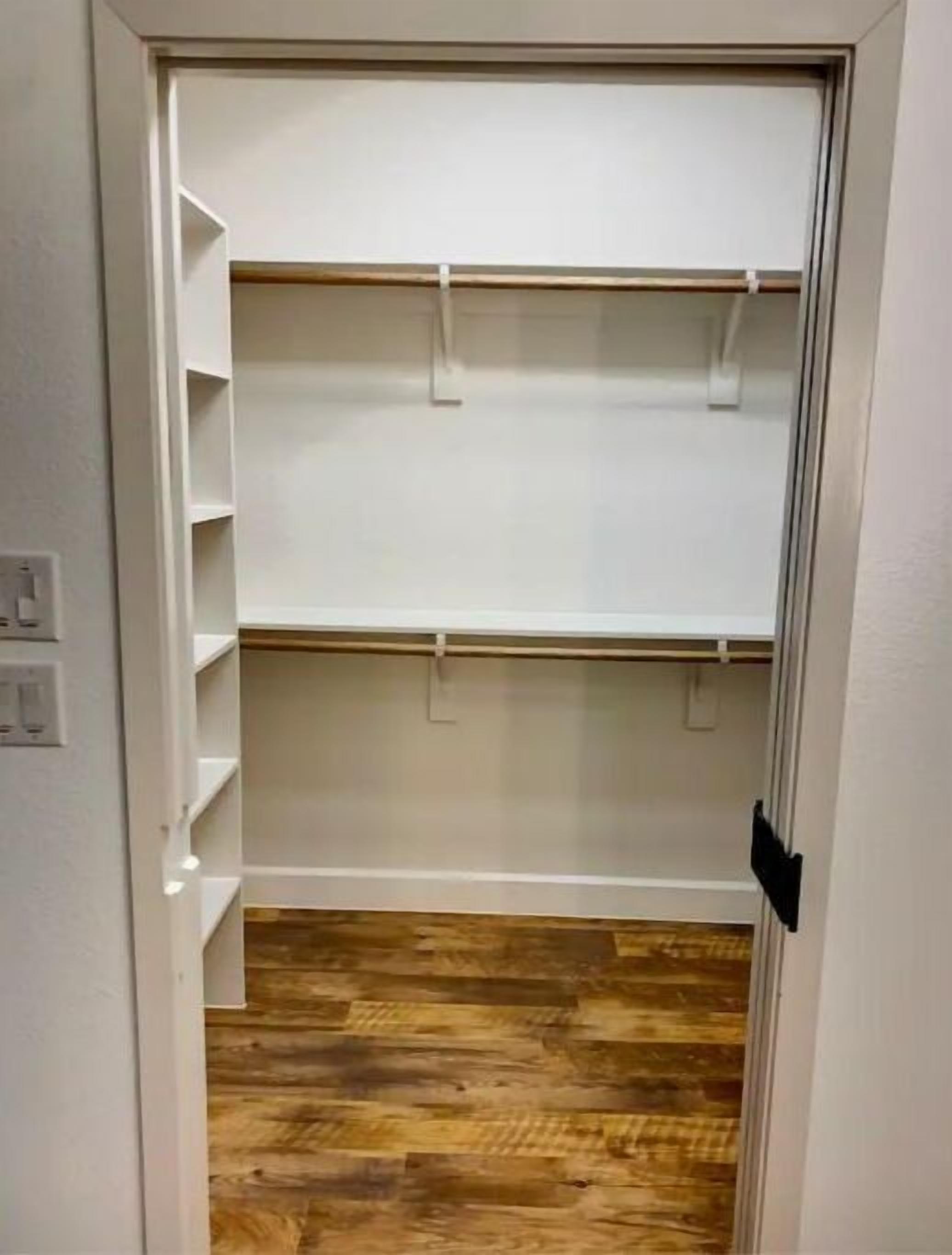 A closet with three shelves and a wooden floor.