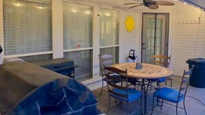 Eine Terrasse mit rundem Tisch und Stühlen, Deckenventilatoren und einer überdachten Sitzgelegenheit.