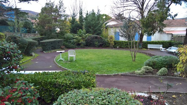 A well-maintained garden with a lawn, a white bench, and a small table.