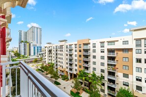 A multi-story residential building with balconies, a clear sky, and a street view.