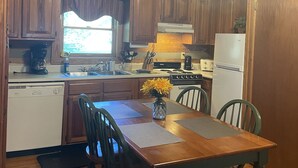 A wooden kitchen with a dining table, chairs, and a ceiling fan.