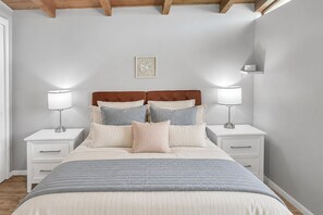 Une chambre à coucher avec un lit, des tables de chevet, des lampes et un tableau accroché au mur.