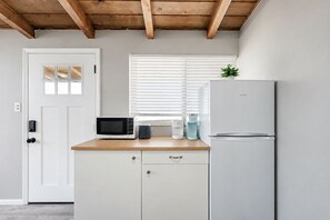 Une cuisine équipée d’un four à micro-ondes, d’un grille-pain et d’un réfrigérateur, avec des poutres en bois au plafond et une porte dotée d’une fenêtre.