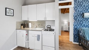 Une cuisine compacte avec des meubles blancs, une cuisinière à gaz, un évier et un petit plan de travail.