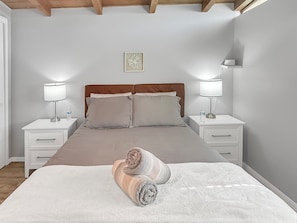 Ein Schlafzimmer mit einem Bett, zwei Nachttischen, einer Kopfteil und einer Wandleuchte.