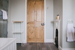 Une porte en bois, des étagères blanches, une cheminée blanche et un porte-serviettes blanc.