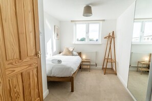 Une chambre avec un lit en bois, une fenêtre, un radiateur et une échelle en bois.