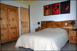 Cozy retreat with a large bed, two nightstands, and a wardrobe, featuring framed artworks above.